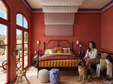 A cozy bedroom featuring a woman relaxing on a bed, designed in a warm, vibrant style with rustic elements, showcasing Homestyler's 3D rendering capabilities to visualize interior design.